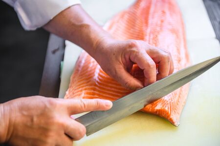 close up chef cutting fresh salmonの写真素材