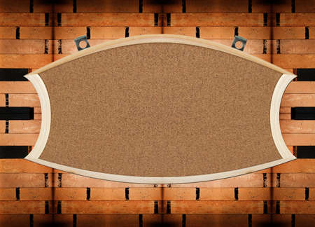 Blank sign made of cork, with metal hager, on wooden wallの写真素材
