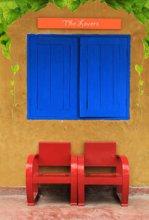 Red vintage chairs against orange wall with leafの写真素材