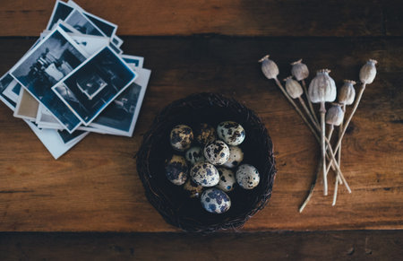 Quail eggs in a basket on a wooden table with old photos