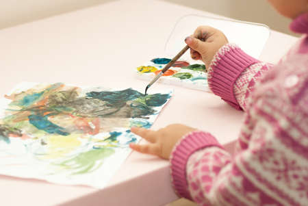 Little girl draws paints on a sheet of paper.の写真素材