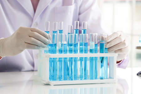 An Asian scientist or chemist drops a blue liquid chemical in a laboratory. Research concepts in...