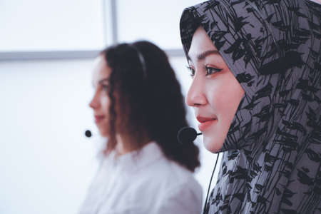 Portrait, close-up, beautiful woman, Muslim receptionist with headset desktop computer in office Talk to customers with service mind. Smile. Business idea. Consulting staff. call center hotlineの写真素材