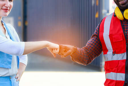 A team of African American men and Caucasian women wear helmets. Handshake to congratulate the successful event. Concept Containers from cargo ships, imports, exports, logistics industry services.の写真素材