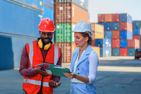A young African-American engineer and Caucasian woman manager monitors and supervises the loading of...