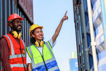 A female engineer and a young African-American man monitor and supervises the loading of containers...
