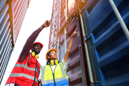 A female engineer and a young African-American man monitor and supervises the loading of containers at a commercial shipping port. Happy to use the concept of teamwork. import-export import-exportの写真素材