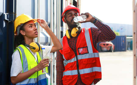 A team of African-American male and female engineers take a break to drink from a bottle. from...