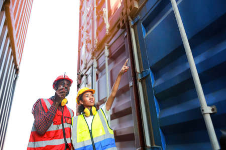 A female engineer and a young African-American man monitor and supervises the loading of containers at a commercial shipping port. Happy to use the concept of teamwork. import-export import-exportの写真素材