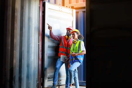 A female engineer and a young African-American man monitor and supervises the loading of containers at a commercial shipping port. Happy to use the concept of teamwork. import-export import-exportの写真素材