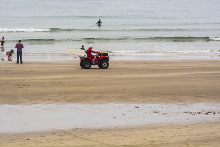 August 18th, 2016 :- A beach guard on patrol of the West Strand Beach, Portrush , Northern Ireland on his Quad Bike. Other Beach Users  can be seen in the backgroundEditorial onlyのeditorial素材