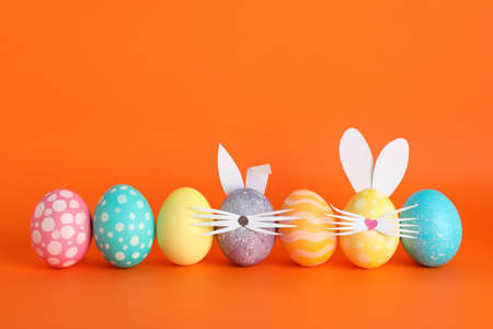 Decorated Easter eggs and cute bunny's ears on color backgroundの写真素材
