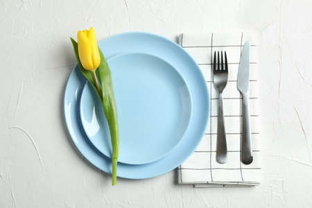 Beautiful tulips and plate with utensils for Mother's Day on light background, top viewの写真素材