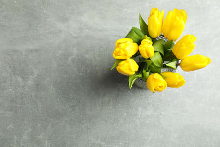 Beautiful bouquet tulips in vase on gray background, top view. Space for textの写真素材