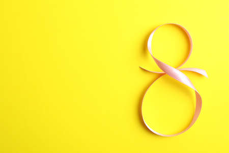 8 March, International Women's Day. Figure eight of pink ribbon on yellow background. Space for textの写真素材
