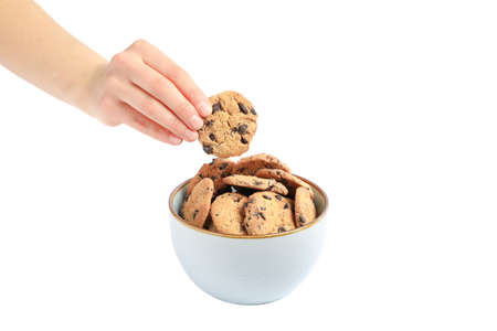 Young woman holding tasty chocolate chip cookie over bowl on white background, closeup