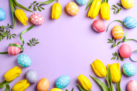 Flat lay composition with Easter eggs, tape and flowers on color background, space for text. Top...
