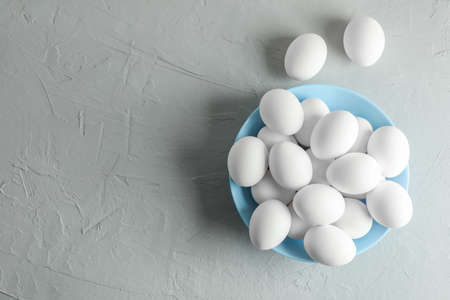 Chicken eggs in plate on gray background, space for text