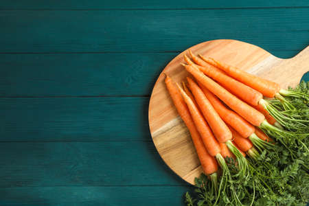 Cutting board with ripe carrots on wooden tableの写真素材