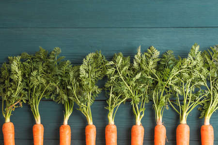 Ripe carrots on wooden background, space for text