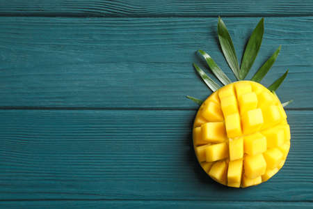 Cut ripe mango and palm leaf on wooden background, space for textの写真素材