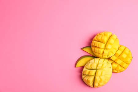 Cut ripe mangoes and space for text on color background, top viewの写真素材