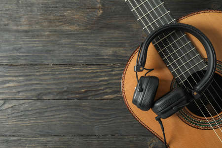 Beautiful classic guitar with headphones on wooden background, space for textの写真素材