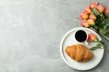 Composition with marble tray, cup of coffee, croissant, roses and space for text on grey background, top viewの写真素材