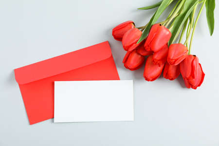 Envelopes with space for text and beautiful red tulips on light grey background, top viewの写真素材