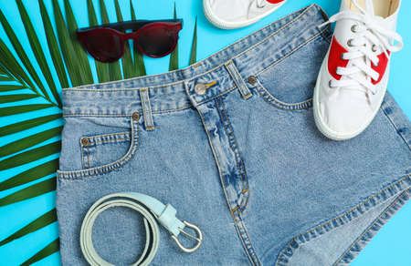 Flat lay composition with: women clothes and accessories, palm leaf on blue background. Summer...