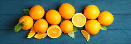 Flat lay composition with ripe oranges and leaves on wooden background. Top view