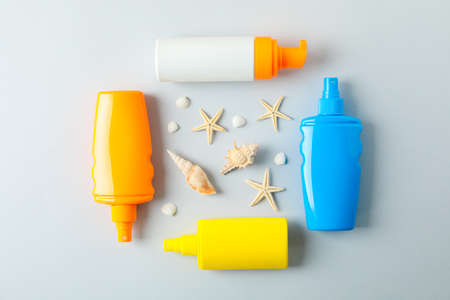 Flat lay composition with sunscreen sprays and starfishes on color background, space for text....