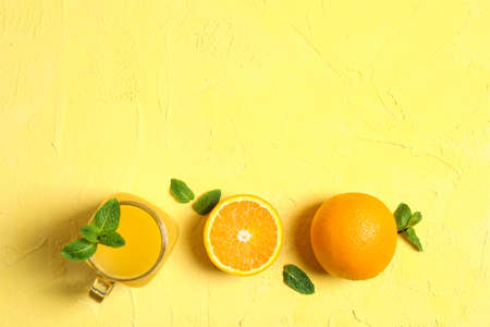 Flat lay composition with orange, mint and glass jar with fresh orange juice on color background, space for text. Fresh natural drinksの写真素材
