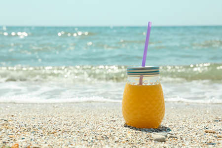 Glass jar of fresh orange juice on seaside, space for text. Summer vacation backgroundの写真素材
