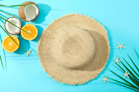 Straw hat, oranges, coconuts, palm leaves and starfishes on color background, space for text and top...