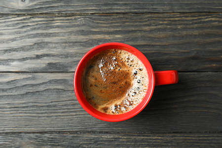 Cup of coffee with frothy foam on wooden background, space for text and top view. Coffee time...