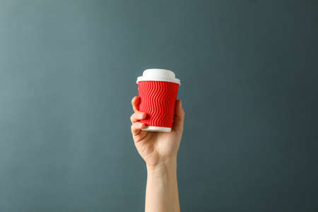 Female hand hold paper glass against black background, space for textの写真素材