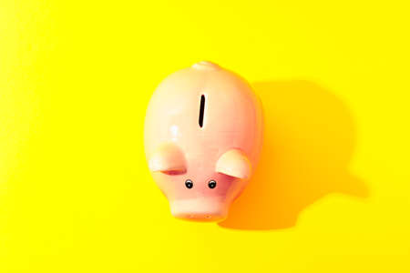 Happy piggy bank on yellow background, space for text and top view. Finance, saving money