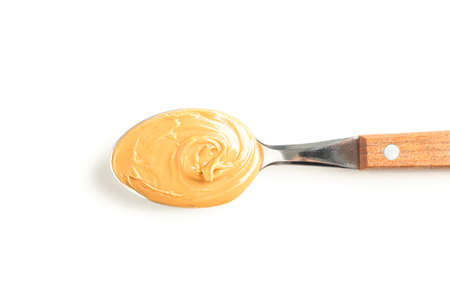 Creamy peanut butter in spoon isolated on white background, top view. A traditional product of American cuisineの写真素材