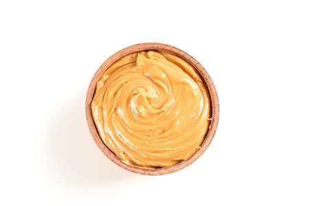 Creamy peanut butter in wooden bowl isolated on white background, top view. A traditional product of...