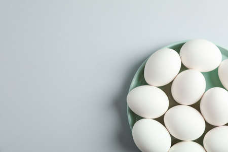 White chicken eggs in plate on grey background, space for text and top viewの写真素材