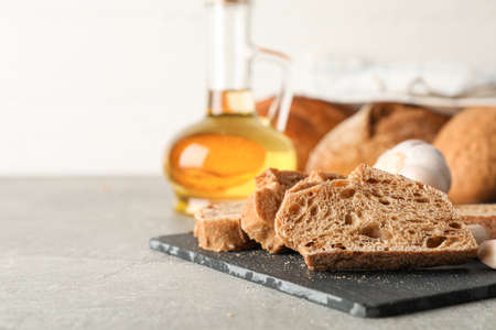 Composition with bakery products, garlic and olive oil on grey background, closeup and space for...