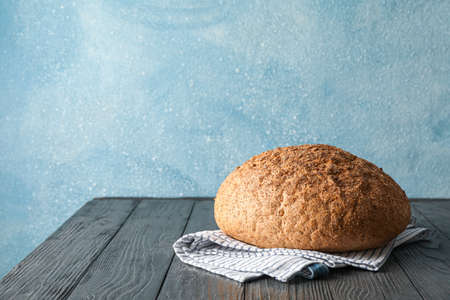 Bread on kitchen towel on wooden table against light background, space for text