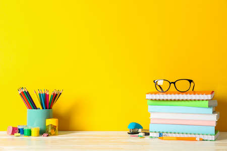 School supplies on wooden table against color background, space for textの写真素材