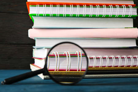 Composition with copybooks and magnifier on wood table against dark backgroundの写真素材