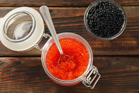 Glass jars with caviar on wooden table, space for textの写真素材