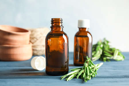 Rosemary oil and leaves, wood bowls on wooden background, space for textの写真素材