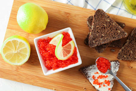 Caviar, bread, lemons and cutting board on light background, top viewの写真素材