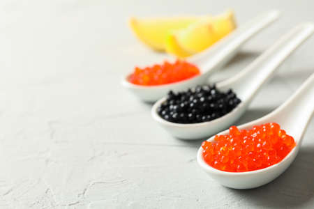 Porcelain spoons with caviar and lemon slices on light backgroundの写真素材