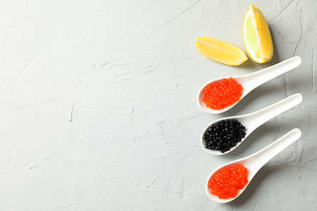 Porcelain spoons with caviar and lemon slices on light backgroundの写真素材